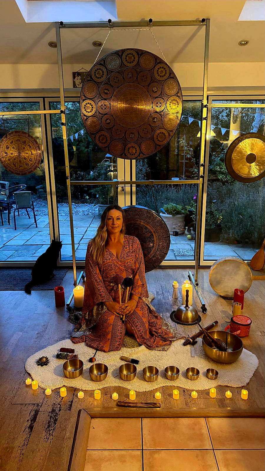 Sally Young seated among her gongs, singing bowls and candles in the sanctuary